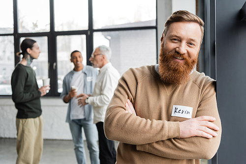 Positive man with name sticker looking at camera during alcoholics meeting in recovery center