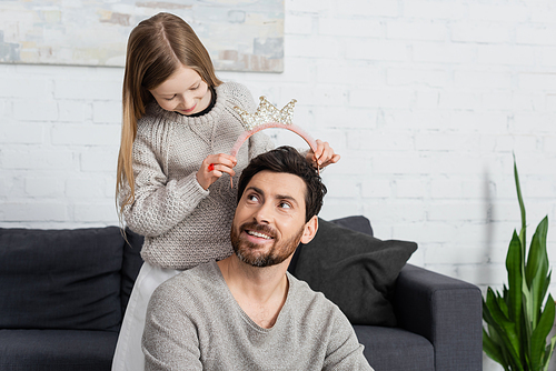 happy kid wearing crown on head of cheerful father with beard