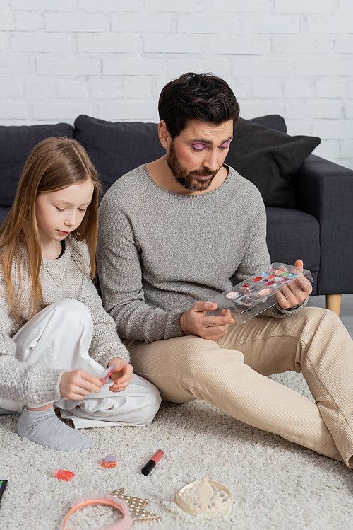 preteen girl playing beauty game with bearded father in living room