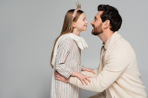 happy bearded father and cute daughter in crown smiling isolated on grey