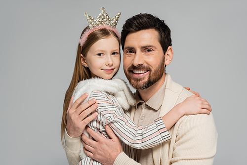 portrait of happy father and daughter in crown smiling while looking at camera isolated on grey