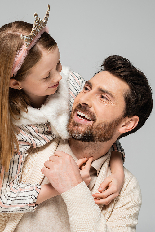 happy kid in crown hugging positive father with beard isolated on grey