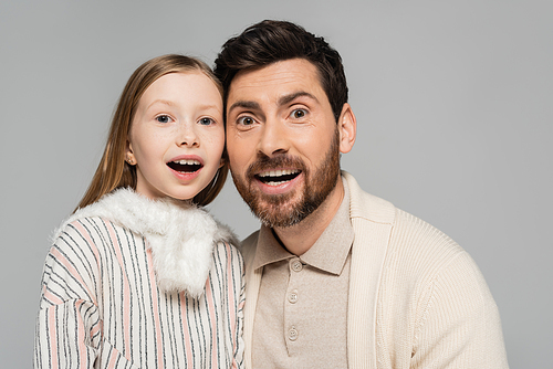 portrait of amazed father and daughter looking at camera isolated on grey