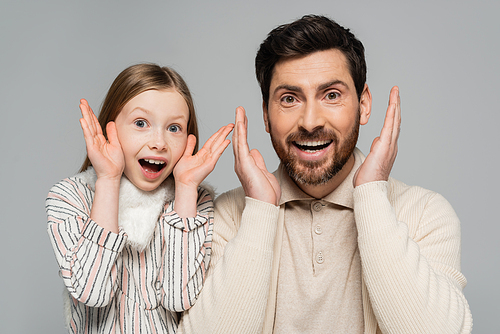 portrait of amazed father and daughter gesturing and looking at camera isolated on grey