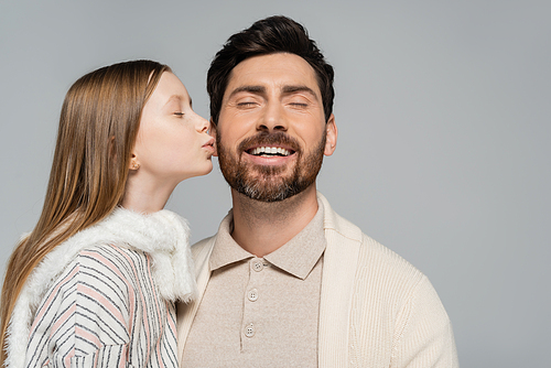 portrait of cheerful kid kissing cheek of father with smiling closed eyes isolated on grey