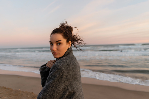 Portrait of curly woman looking at camera on beach in Spain