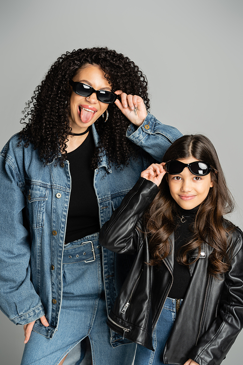 Fashionable parent and daughter posing with sunglasses isolated on grey