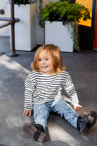 happy toddler child sitting on porch at backyard next to house in Miami