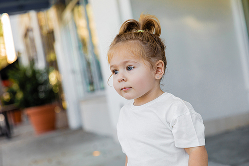 portrait of toddler girl with grey eyes looking away on street in Miami