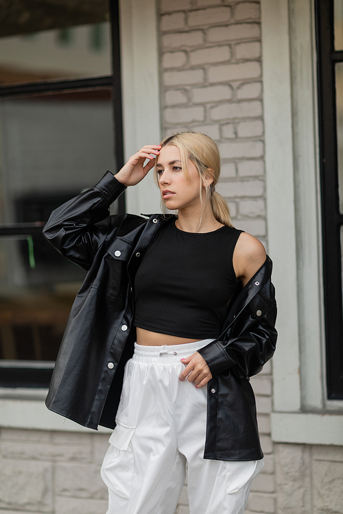 pretty woman in leather shirt jacket and cargo pants standing near building on street in Miami