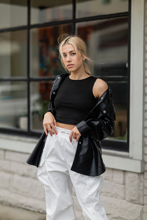 pretty woman in black leather shirt jacket and cargo pants standing near building on street in Miami