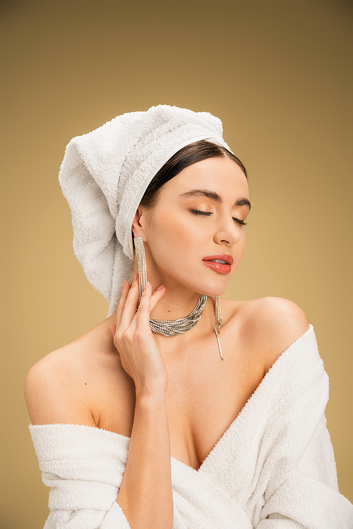 elegant young woman with closed eyes and towel on head on beige background