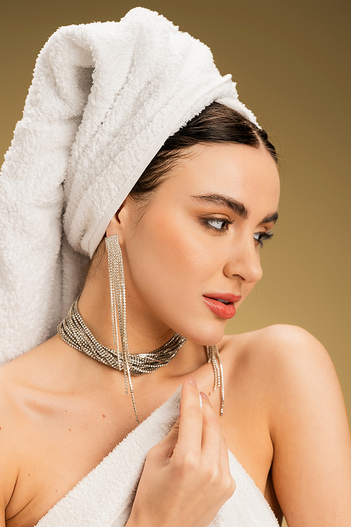 portrait of charming woman in jewelry holding white towel on beige background