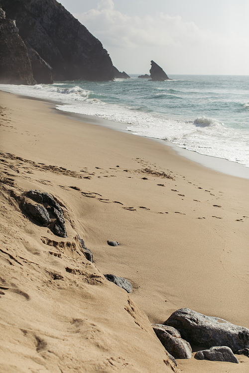 stones on wet sandy european beach near ocean in portugal