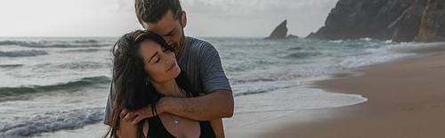happy man hugging smiling girlfriend near ocean in portugal, banner