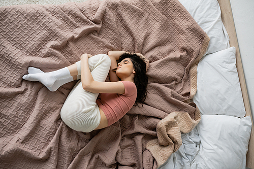 Top view of lonely woman in pajama lying on bed at home