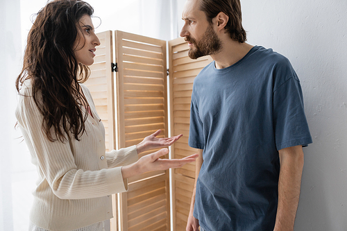 Side view of brunette woman talking to angry boyfriend at home