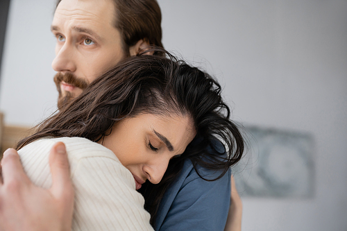 Caring man hugging and consoling sad brunette girlfriend at home