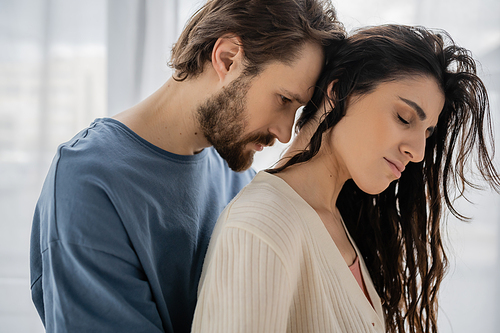 Bearded man standing near brunette girlfriend at home