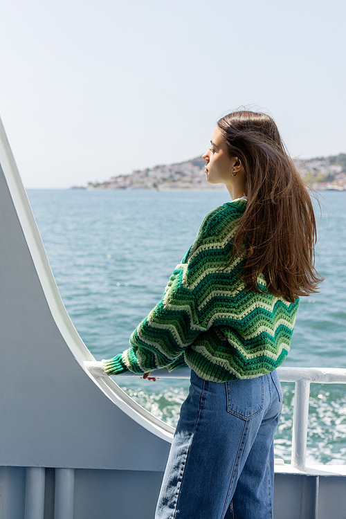 Side view of brunette woman in sweater standing on ferry boat with sea and Princess islands at background