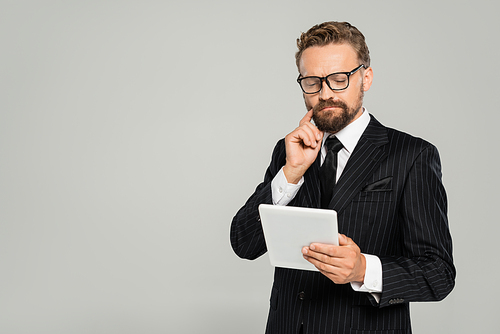 bearded businessman in formal wear and glasses using digital tablet isolated on grey