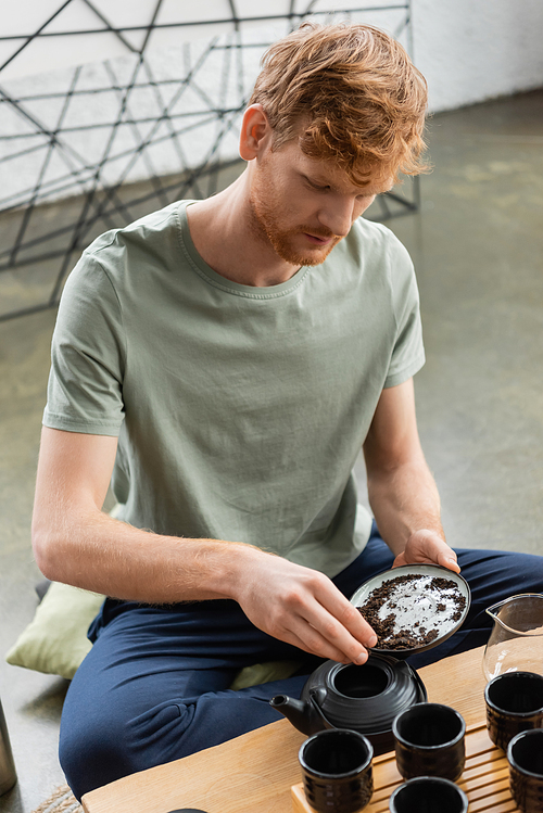 redhead man with beard adding puer tea leaves in Chinese tea pot