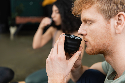 side view of redhead man holding Chinese cup and smelling brewed puer tea