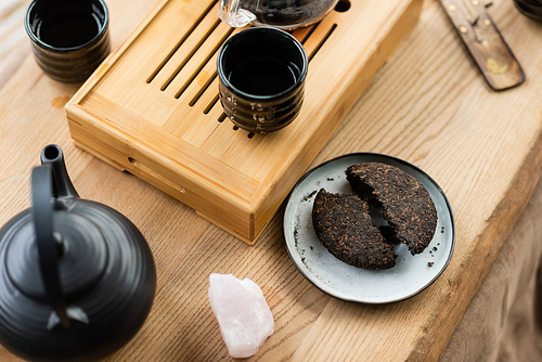 top view of compressed pu-erh tea on plate near Japanese teapot and cups in yoga studio