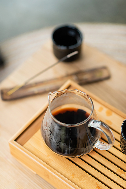 high angle view of focused brewed puer tea in glass jug on wooden stand