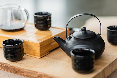 traditional japanese teapot near cups and glass jug with puer tea on blurred background