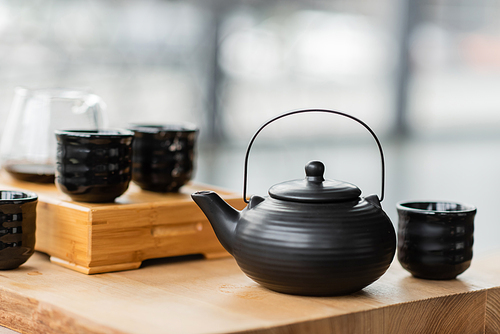 traditional Chinese teapot near cups and glass jug with puer tea on blurred background