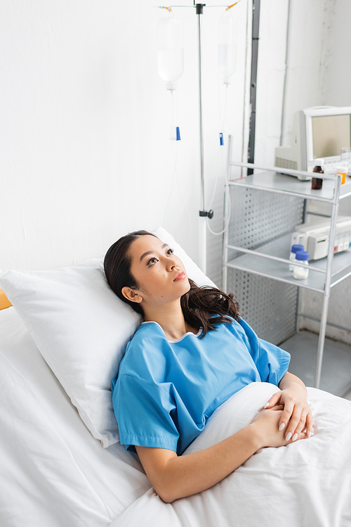 high angle view of sick and stressed asian woman lying on hospital bed and looking away