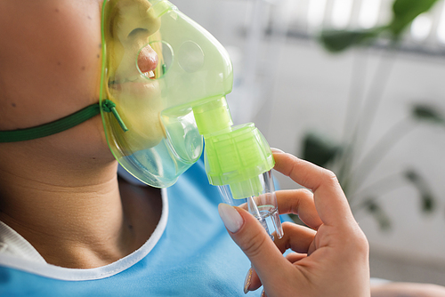 cropped view of diseased woman breathing in oxygen mask in hospital ward