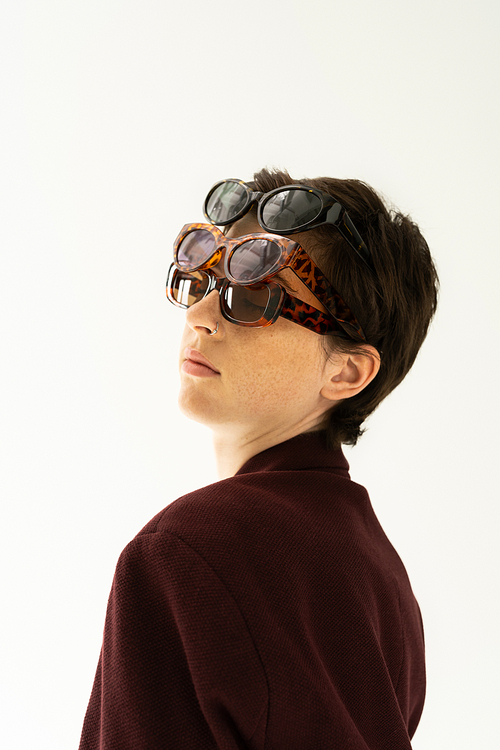 portrait of brunette woman wearing several different sunglasses isolated on grey