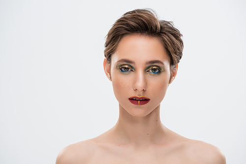 young woman with short hair and bright makeup standing with bare shoulders isolated on grey