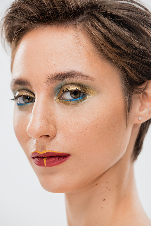 close up view of young model with bright makeup looking at camera isolated on grey