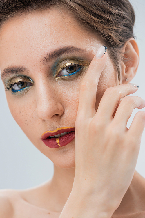 close up of young woman with golden and blue eye makeup isolated on grey