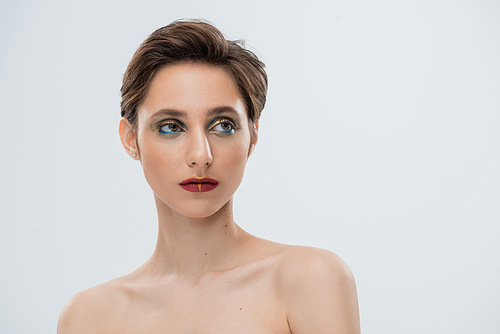 portrait of young woman with shiny makeup and short hair isolated on grey