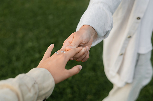 partial view of yoga man in white linen clothes holding hand of young woman outdoors