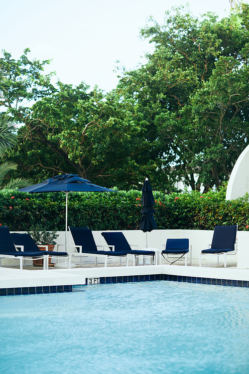 luxury resort, vacation and holiday concept, sunbeds and outdoor chairs near umbrellas around green tropical palm trees and plants next to outdoor swimming pool in hotel, summer