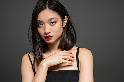 portrait of elegant asian woman with red lips looking at camera isolated on grey