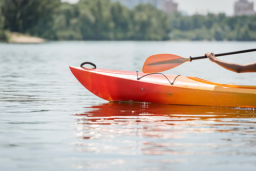 cropped view of hand of active african american woman with paddle sailing in sportive kayak on calm river during water recreation on summer weekend, summer fun