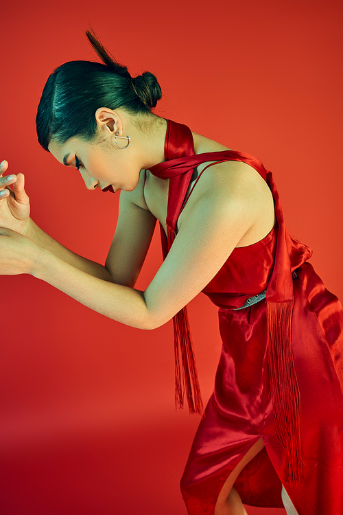 stylish asian fashion model with trendy hairstyle and bold makeup posing in elegant dress and neckerchief on red background, trendy spring, charming, glamour, graceful, generation z