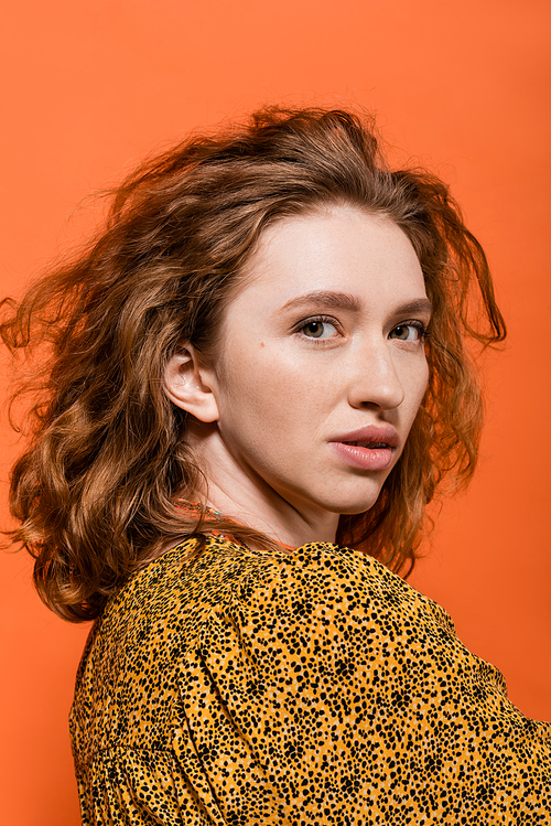 Portrait of stylish redhead woman with no-makeup look posing in yellow blouse and looking at camera isolated on orange, stylish casual outfit and summer vibes concept, Youth Culture