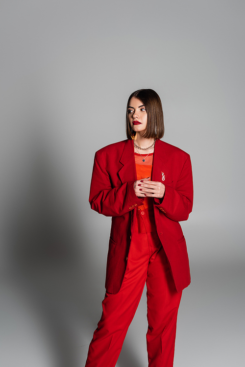 lady in red, young brunette woman with short hair and nose piercing posing in suit on grey background, generation z, executive style, fashionable model, professional attire, executive style
