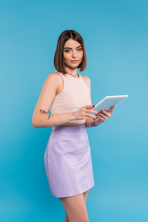 brunette young woman with short hair, tattoos and nose piercing digital tablet laptop on blue background, generation z, summer trends, attractive, social media influencers, tablet user