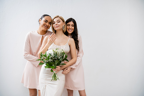 special occasion, bridesmaids hugging bride, friendship goals, grey background, happy multicultural girlfriends, cultural diversity, bridal bouquet, bridal party, blonde and brunette women