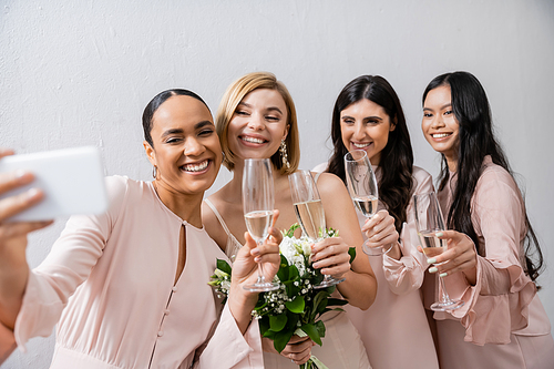 four women taking selfie, cheerful bride and her interracial bridesmaids,  happiness, champagne glasses, bridal bouquet, wedding dress, bridesmaid gown, brunette and blonde women