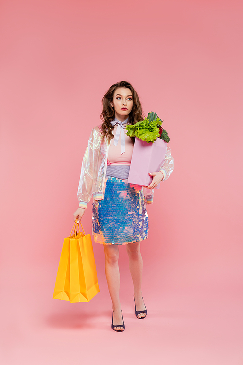 beautiful young woman carrying shopping bags and grocery bag, standing on pink background, conceptual photography, home duties, food and vegetables, housewife concept