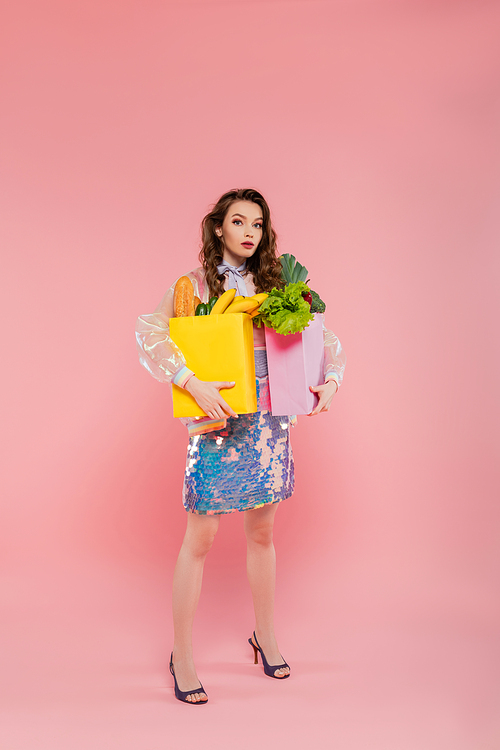 housewife duties, attractive young woman carrying paper bags with groceries, model with wavy hair standing on pink background, conceptual photography, home duties, stylish wife